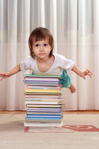 Pequeña chica caucásica acostada en un montón de libros —  Fotos de Stock