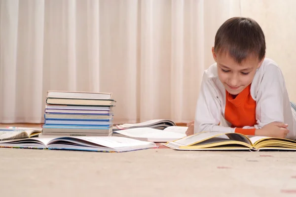 Mały chłopiec kaukaski leżący za stos książek — Zdjęcie stockowe