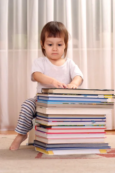 Little Caucasian baby sitting behind a stack of books — Stock Photo, Image