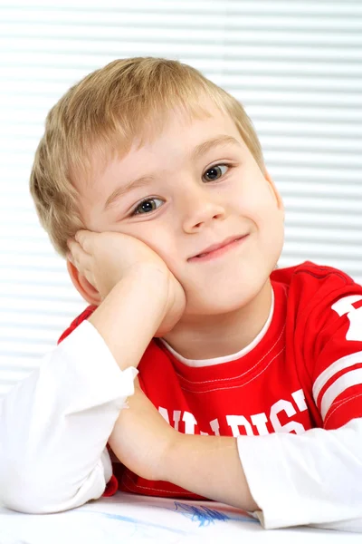 A little boy sitting at a table — Stock Photo, Image
