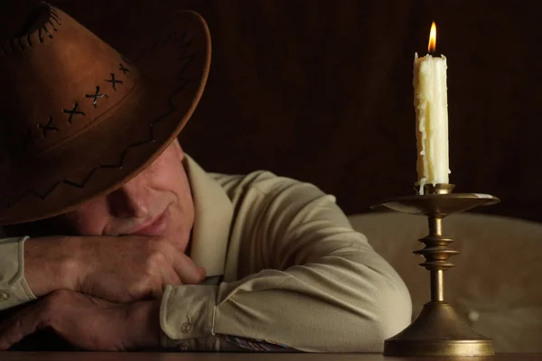 Hombre caucásico guapo se sienta en una mesa con una vela — Foto de Stock