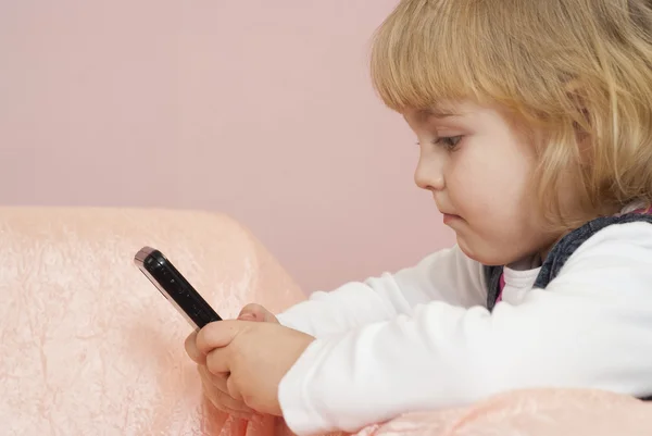 Красивая маленькая девочка играет с телефоном — стоковое фото