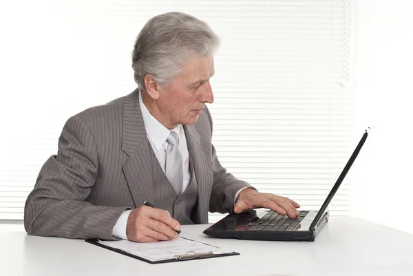 Een oudere man zit op de computer — Stockfoto