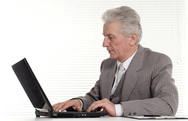 Een oudere man zit op de laptop — Stockfoto