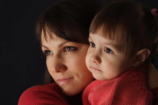 En smuk kaukasisk dejlig mor holder sin datter i hendes ar - Stock-foto