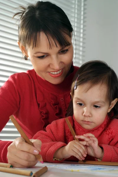 A beautiful Caucasian mom and daughter holding pencils — Stock Photo, Image