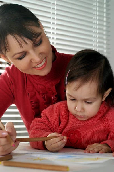 A beautiful Caucasian mum and daughter holding pencils — Stock Photo, Image