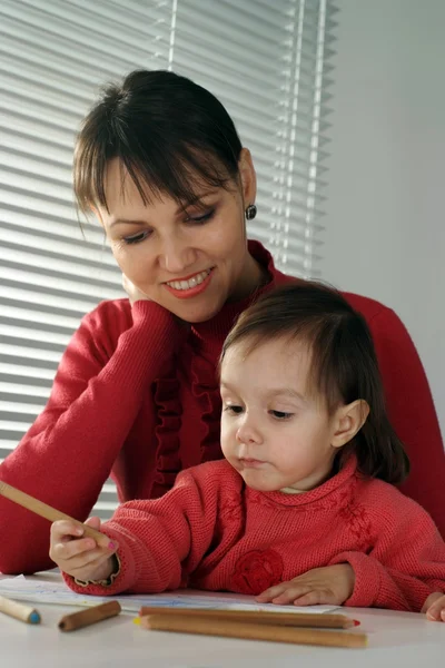 A beautiful Caucasian happy mom and daughter holding pencils — Stock Photo, Image