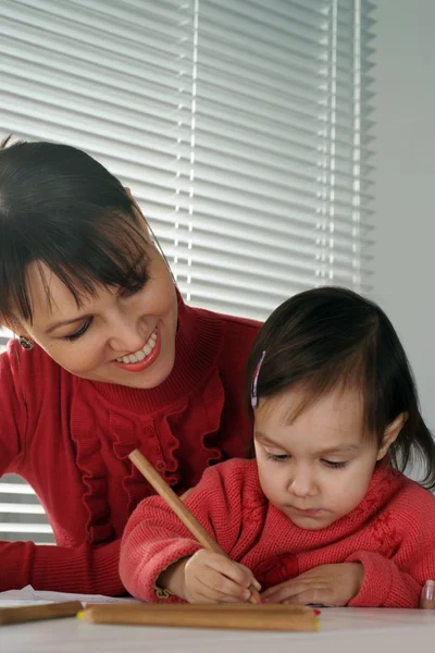 A beautiful Caucasian smile mama and daughter holding pencils — Stock Photo, Image
