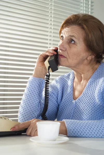 Beautiful Caucasian aged woman with a cup and a telephone — Stock Photo, Image