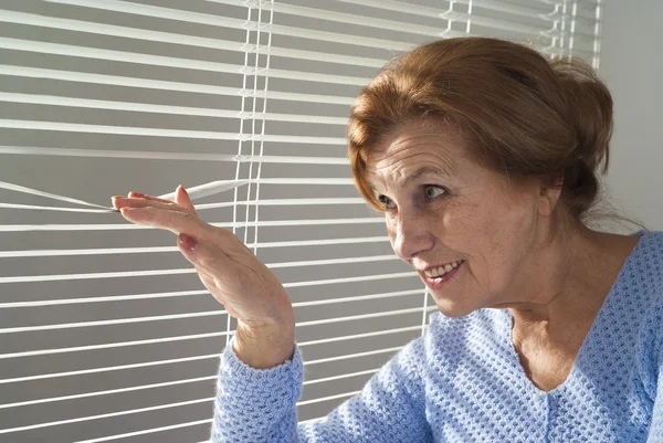 Una anciana mira por la ventana —  Fotos de Stock