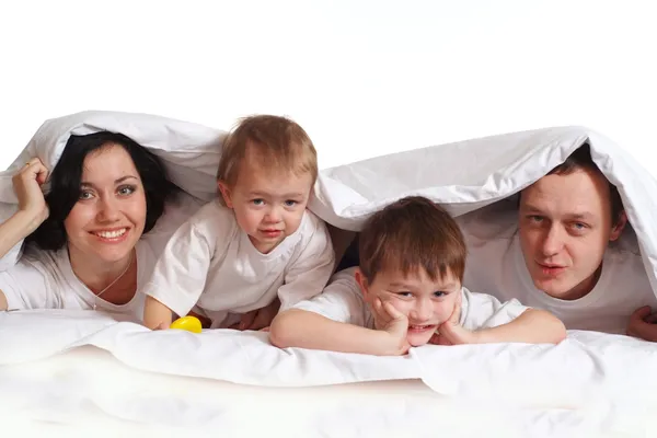 A family of four is under a blanket — Stock Photo, Image