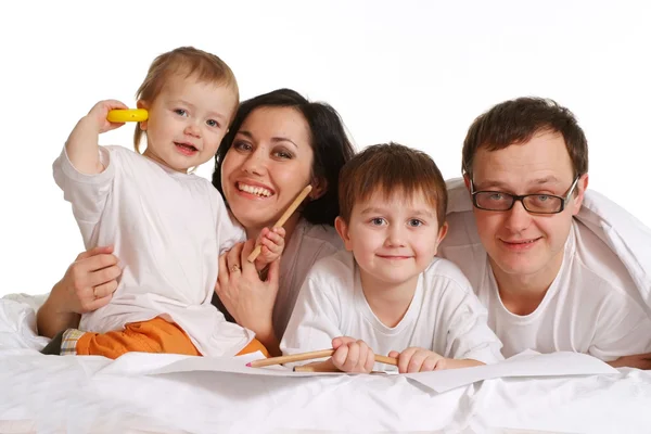 Una familia feliz de cuatro tumbados en la cama — Foto de Stock