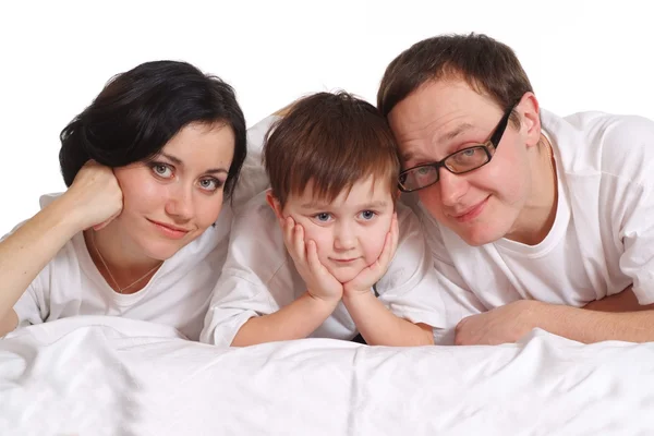Family of three in white shirts on the bed — Stock Photo, Image