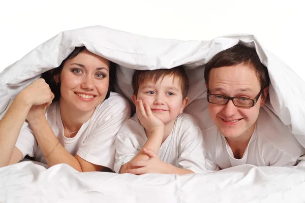 Family of three under a blanket on the bed — Stock Photo, Image