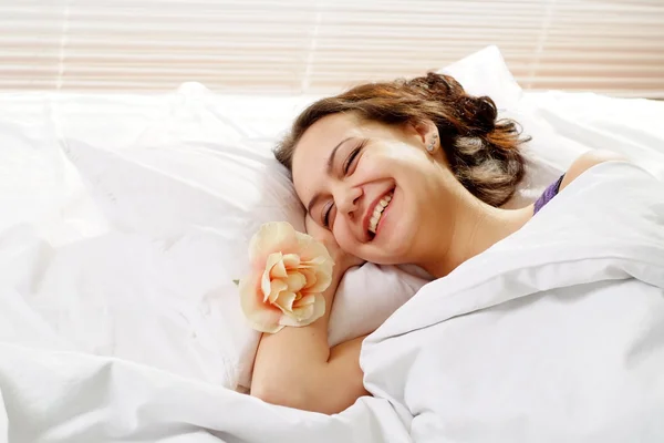 Güzel bir gülümseme beyaz kız yatakta çiçek — Stok fotoğraf