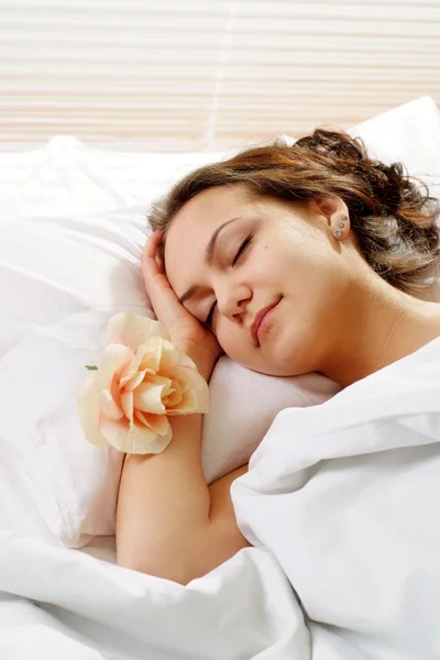 A beautiful caucasian girl with a flower in a bed — Stock Photo, Image