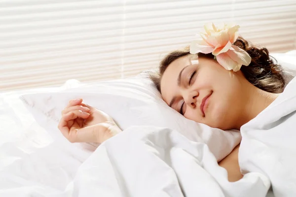 Una hermosa chica de misericordia caucásica con una flor en una cama —  Fotos de Stock