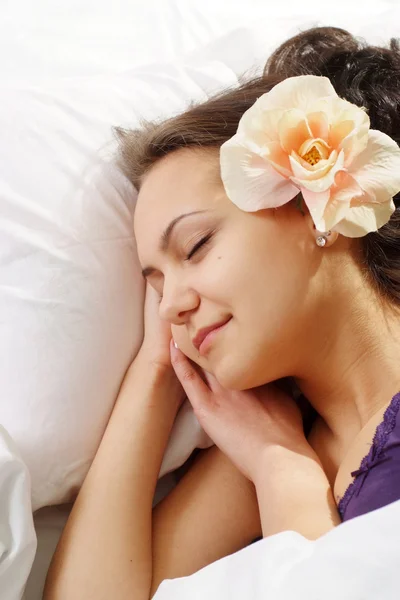 Красивая кавказская счастливая девушка с цветком в постели — стоковое фото
