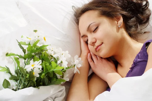 A beautiful caucasian nice girl in bed with a bouquet of flowers — Stock Photo, Image