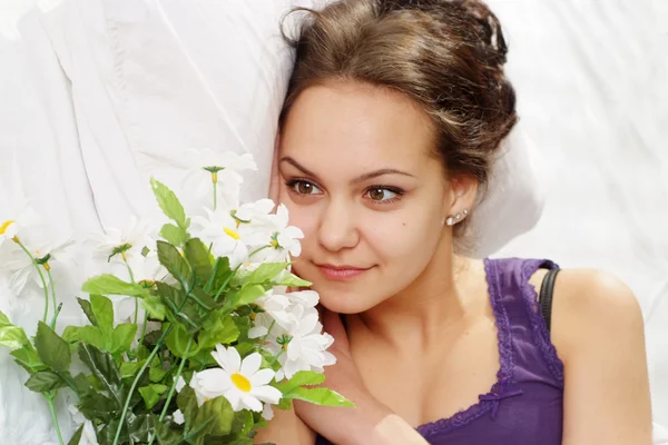 Una hermosa chica caucásica feliz en la cama con un ramo de flores —  Fotos de Stock