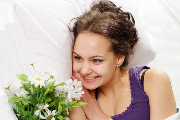 Bir buket çiçek ile yatakta bir güzel beyaz şans kız — Stok fotoğraf
