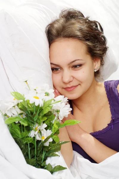 Uma bela menina caucasiana felicidade na cama com um buquê de flor — Fotografia de Stock