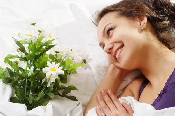 Güzel beyaz servet kız yatakta akışı bir buket — Stok fotoğraf