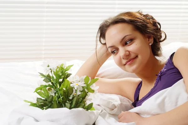 Krásná kavkazské radost holka v posteli s kyticí flo — Stock fotografie