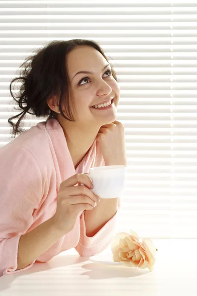 Happy girl with a cup sits — Stock Photo, Image