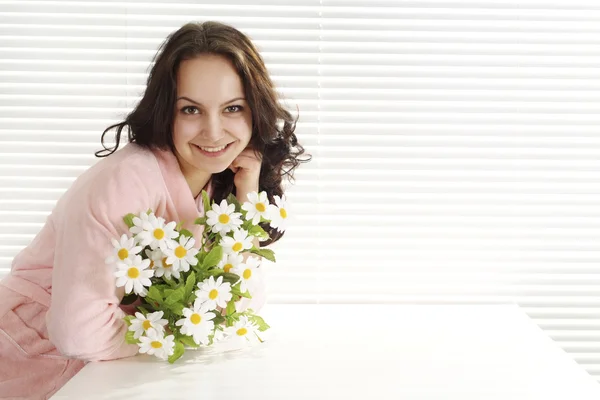 Happy girl with flowers sits — Stock Photo, Image