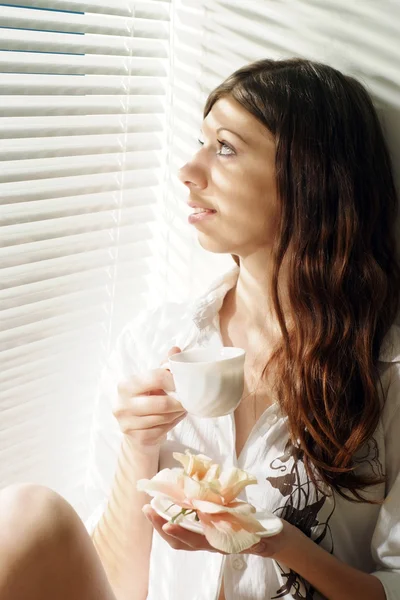 Beautiful girl sitting with a cup and looking — Stock Photo, Image