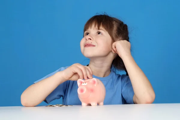 Het kleine meisje zetten een munt in een piggy bank — Stockfoto