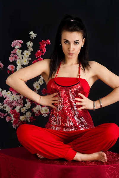 Ein schönes kaukasisches Mädchen sitzt in einem roten Kleid — Stockfoto
