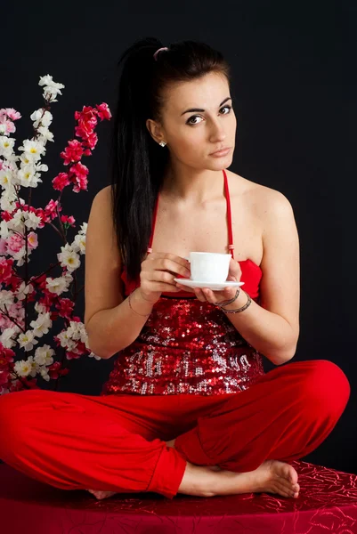 Una hermosa chica caucásica bonita sentada en un vestido rojo —  Fotos de Stock