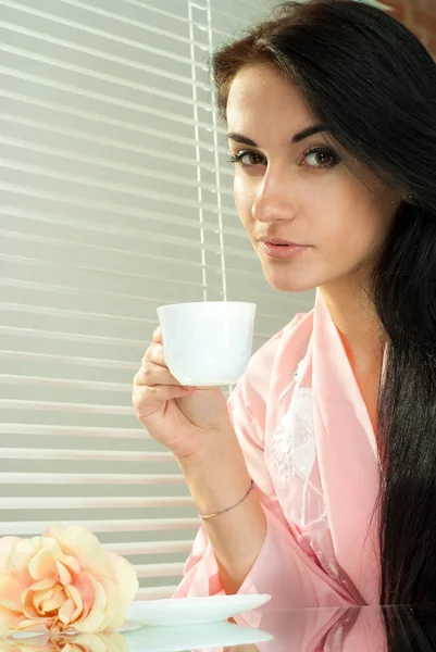 Gyönyörű szép női kaukázusi, ül egy asztalnál egy csésze — Stock Fotó