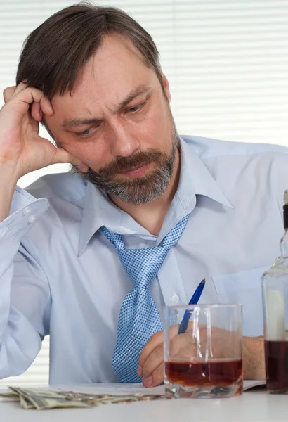 Sorrow businessman sitting at a table with a bottle — Stock Photo, Image