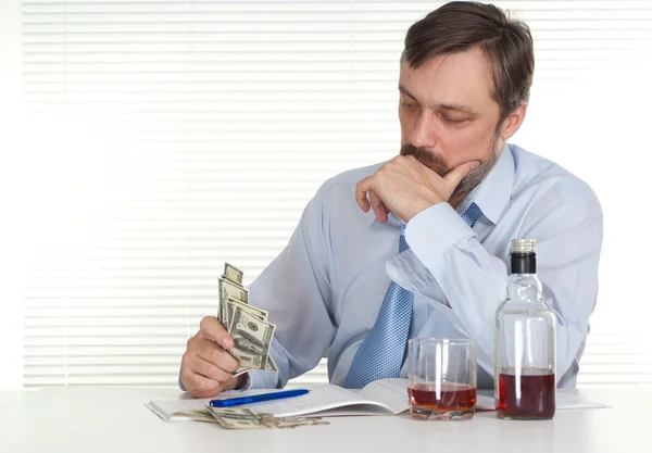 Obchodní muž sedí u stolu s lahví a peníze — Stock fotografie