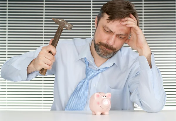 Business man sitting breaks piggy bank — Stock Photo, Image