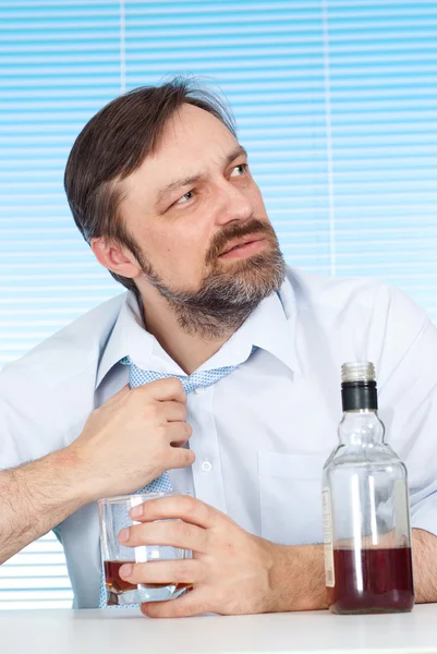 Problemas homem de negócios sentado em uma mesa com uma garrafa — Fotografia de Stock