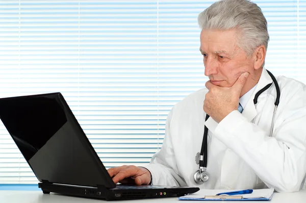 Boldog kaukázusi orvos egy laptop ül — Stock Fotó
