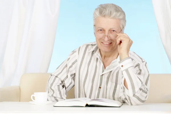 Beautiful old Caucasian man with book sits — Stock Photo, Image