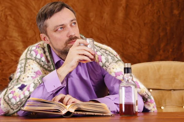 Чоловік п'є віскі і читає — стокове фото