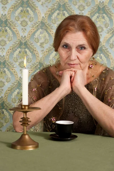 Красивая белая пожилая женщина сидит за столом — стоковое фото