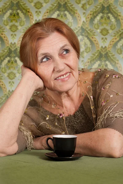 Beautiful Caucasian old woman sitting at a table — Stock Photo, Image