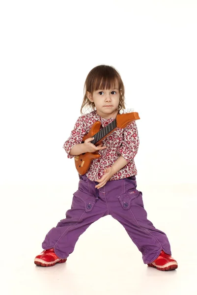 Feliz menina caucasiana brinca com uma guitarra — Fotografia de Stock