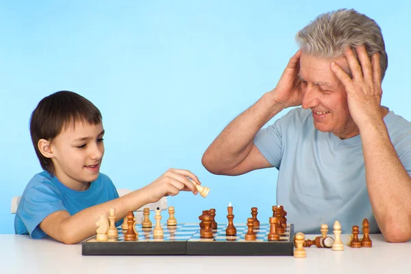 Happy Caucasian grandfather with his grandson plays chess agains — Stock Photo, Image
