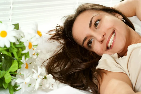 Kavkazská dívka leží v posteli s květinami — Stock fotografie