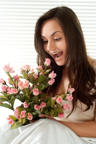 Jonge Kaukasische vrouw zitten in bed met bloemen — Stockfoto