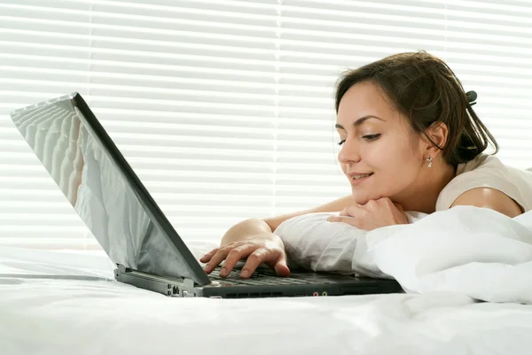 Fiatal kaukázusi nő feküdt az ágyban laptop — Stock Fotó